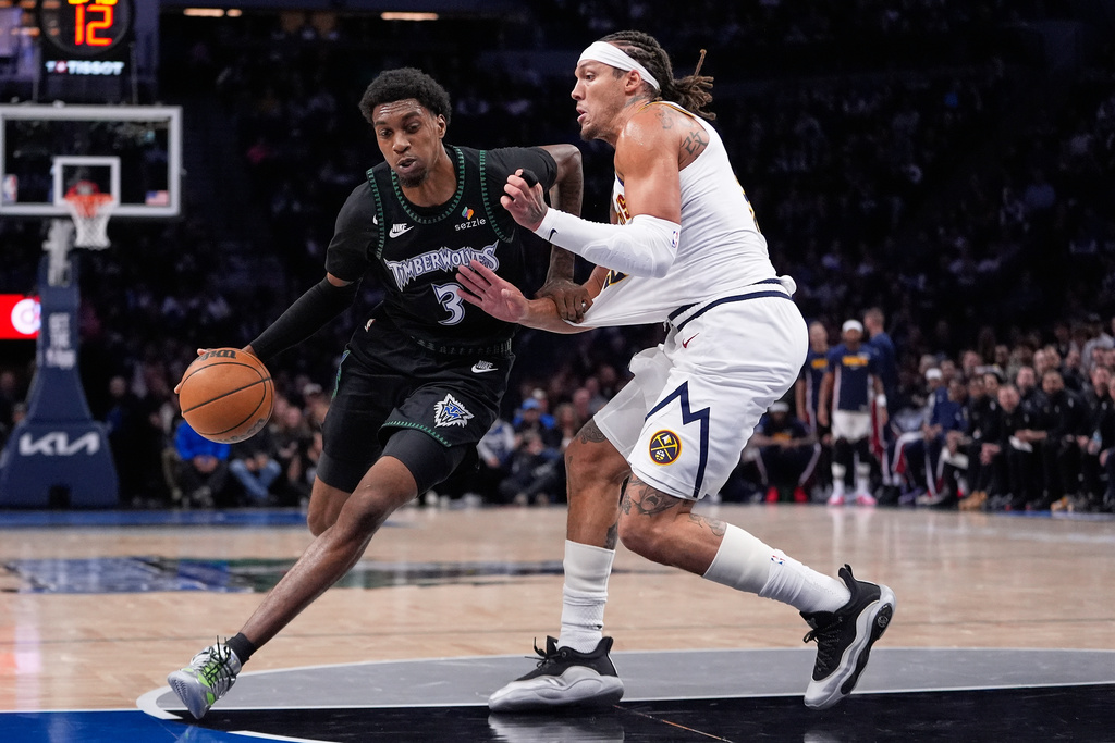 Minnesota Timberwolves forward Jaden McDaniels (3) works toward the basket as Denver Nuggets forward Aaron Gordon, right, defends during the first half of an NBA basketball game, Monday, Oct. 27, 2025, in Minneapolis. (AP Photo/Abbie Parr)