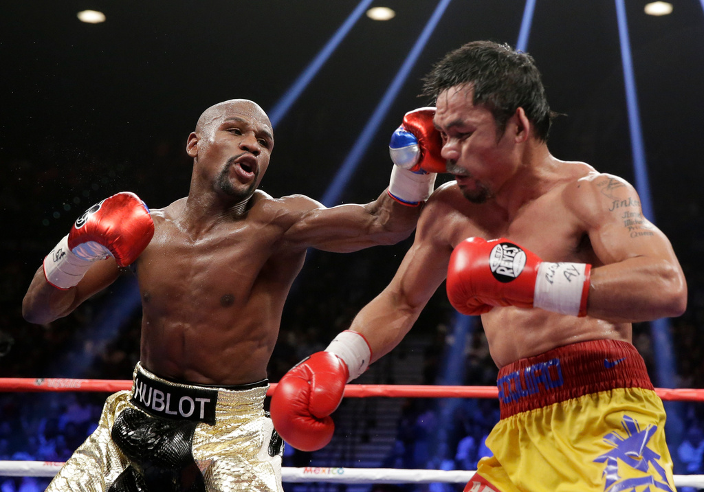 FILE - Floyd Mayweather Jr., left, hits Manny Pacquiao, from the Philippines, during their welterweight title fight on May 2, 2015, in Las Vegas. (AP Photo/Isaac Brekken, File)