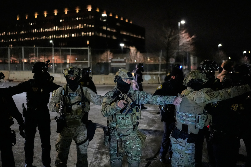 Federal immigration officers confront protesters outside Bishop Henry Whipple Federal Building, Thursday, Jan. 15, 2026, in Minneapolis. (AP Photo/Yuki Iwamura)