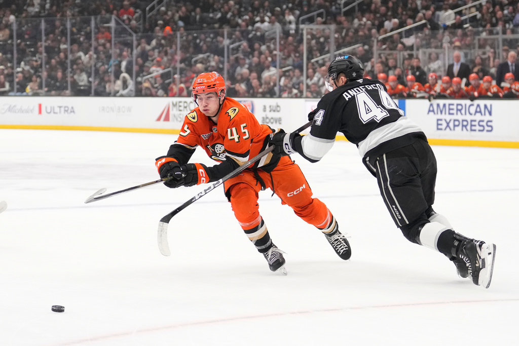 Anaheim Ducks right wing Beckett Sennecke, left, passes the puck while under pressure from Los Angeles Kings defenseman Mikey Anderson during the first period of an NHL hockey game Friday, Jan. 16, 2026, in Los Angeles. (AP Photo/Mark J. Terrill)