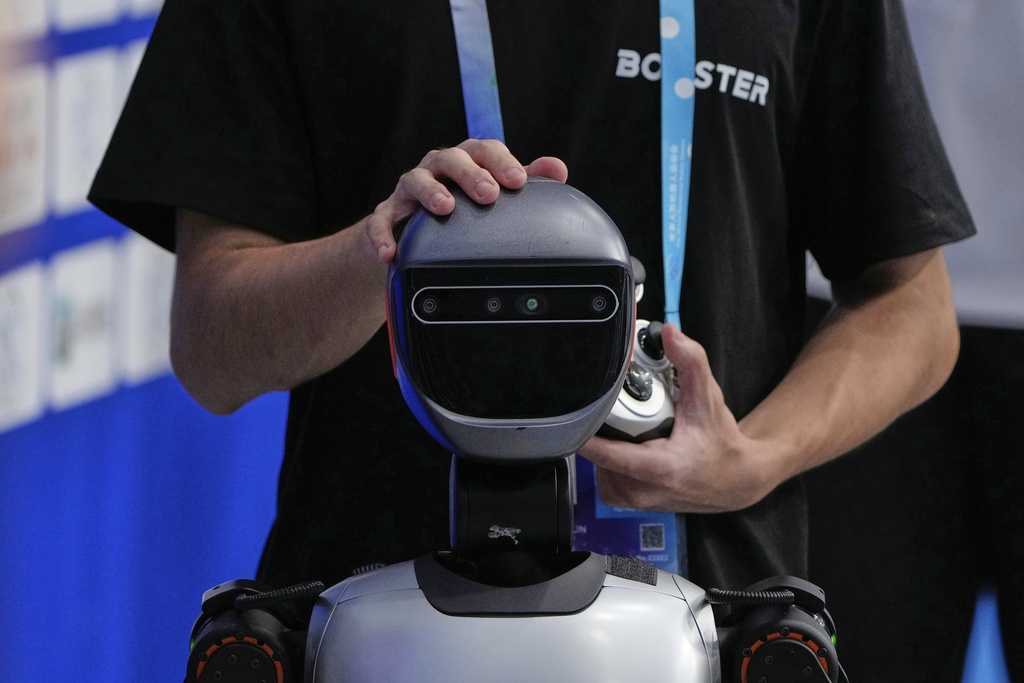 A technician examines the head of a robot at the World Humanoid Robot Games Beijing, China, Saturday, Aug. 16, 2025. (AP Photo/Mahesh Kumar A.)
