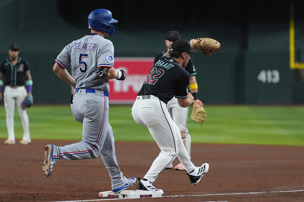 Texas Rangers'Corey Seager (5) reaches first base safely as Arizona Diamondbacks starting pitcher Brandon Pfaadt (32) has his foot off the base during the fifth inning of a baseball game, Saturday, Sept. 12, 2026, in Phoenix. (AP Photo/Ross D. Franklin)