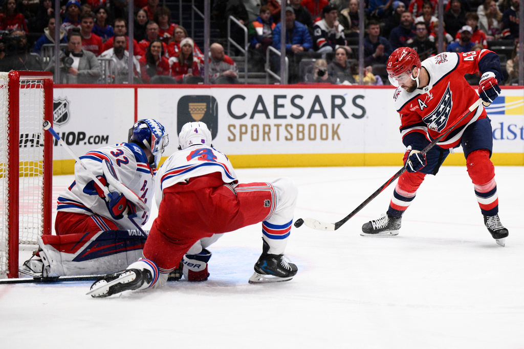 Washington Capitals right wing Tom Wilson (43) shoots the puck for a goal against New York Rangers goaltender Jonathan Quick (32) and defenseman Braden Schneider (4) during the second period of an NHL hockey game, Wednesday, Dec. 31, 2025, in Washington. (AP Photo/Nick Wass)