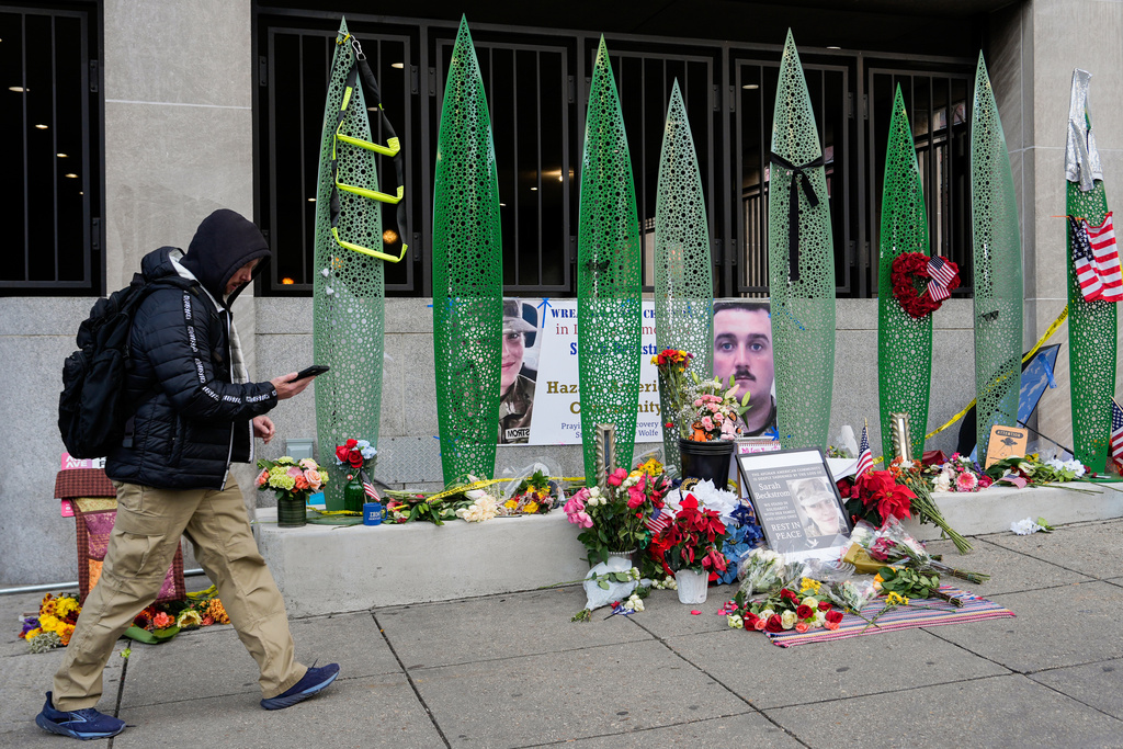A person walks past a makeshift memorial for U.S. Army Spc. Sarah Beckstrom and U.S. Air Force Staff Sgt. Andrew Wolfe outside of Farragut West Station, near the site where the two National Guard members were shot, Monday, Dec. 1, 2025, in Washington. (AP Photo/Julia Demaree Nikhinson)