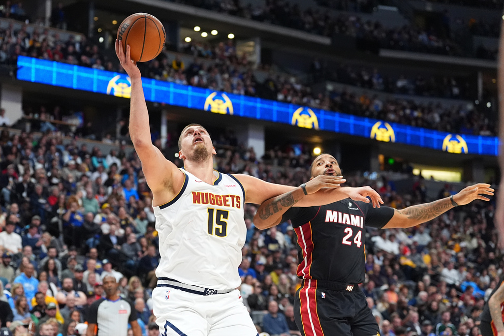 Denver Nuggets center Nikola Jokic, left, goes up for a basket as Miami Heat guard Norman Powell defends in the second half of an NBA basketball game Wednesday, Nov. 5, 2025, in Denver. (AP Photo/David Zalubowski)