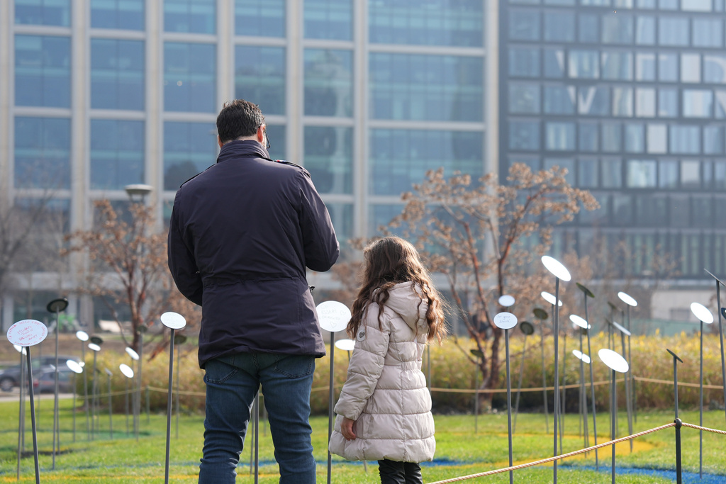 Anthony Cardamone walks with his daughter among mirrored flowers during “Together to Reflect,” an interactive community art project by BAM, the acronym for Biblioteca degli Alberi Milano, a public park in central Milan inviting the public to share thoughts on the values of sport, during the 2026 Winter Olympics, in Milan, Italy, Sunday, Feb. 8, 2026. (AP Photo/María Teresa Hernández)