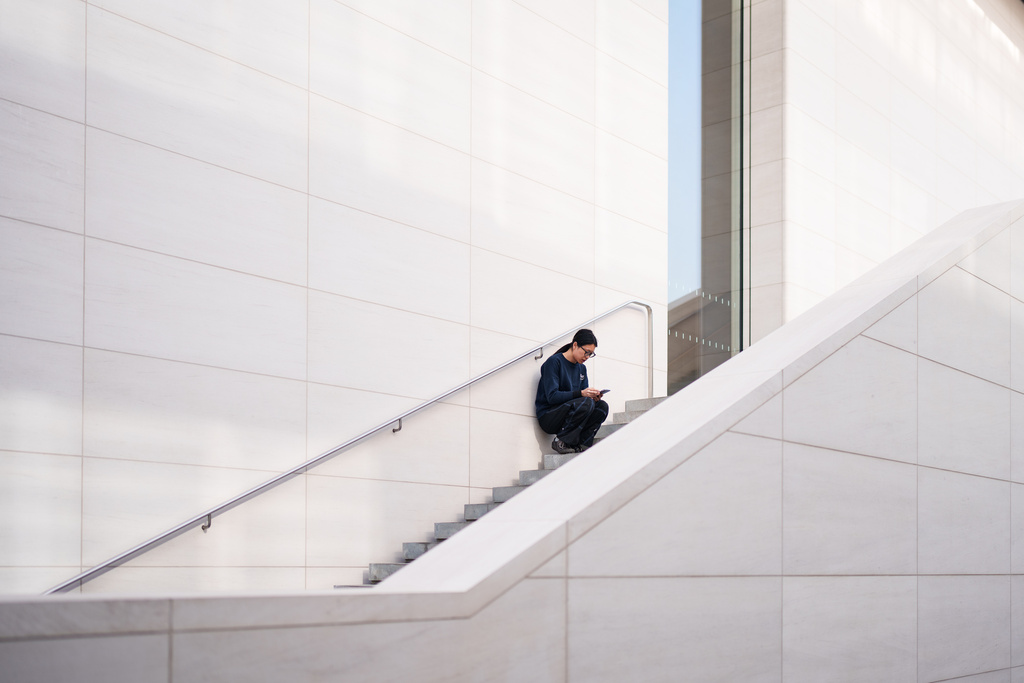 A woman checks phone sitting on a stairway outside a shopping mall in Beijing, China, Thursday, Jan. 15, 2026. (AP Photo/Vincent Thian)