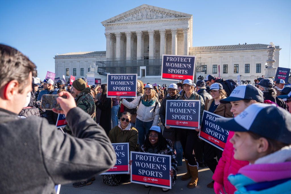 Protesters gather outside the Supreme Court as it hears arguments over state laws barring transgender girls and women from playing on school athletic teams, Tuesday, Jan. 13, 2026, in Washington. (AP Photo/Julia Demaree Nikhinson)