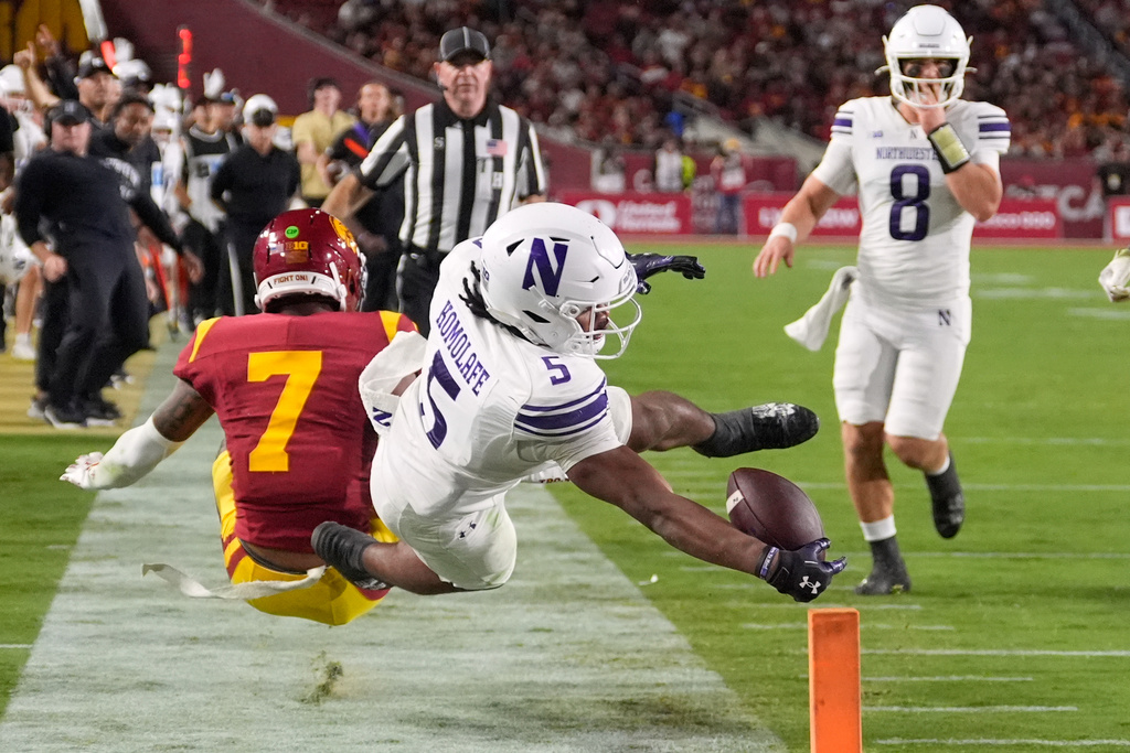 Northwestern running back Caleb Komolafe, center, dives just short of a touchdown as Southern California safety Kamari Ramsey, left, defends and quarterback Preston Stone watches during the first half of an NCAA college football game, Friday, Nov. 7, 2025, in Los Angeles. (AP Photo/Mark J. Terrill)