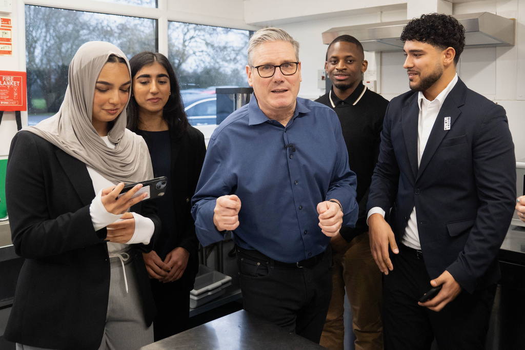 Britain's Prime Minister Keir Starmer, center, speaks with locals, during a visit to a community group at Flaunden Village Hall to discuss the government's Warm Homes Plan, in Flauden, Hertfordshire, England, Thursday, Jan. 22, 2026. (Stefan Rousseau, Pool Photo via AP)