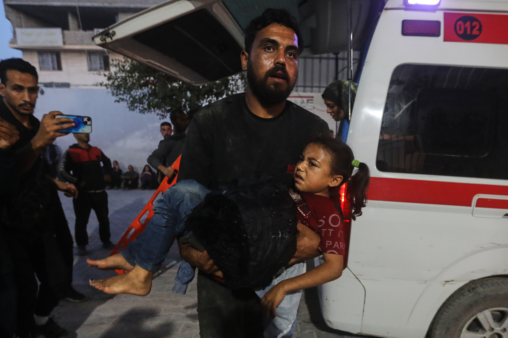 A Palestinian man carries a wounded girl into al-Shifa Hospital following Israeli strikes on the Gaza Strip, Saturday, Nov. 22, 2025. (AP Photo/Yousef Al Zanoun)