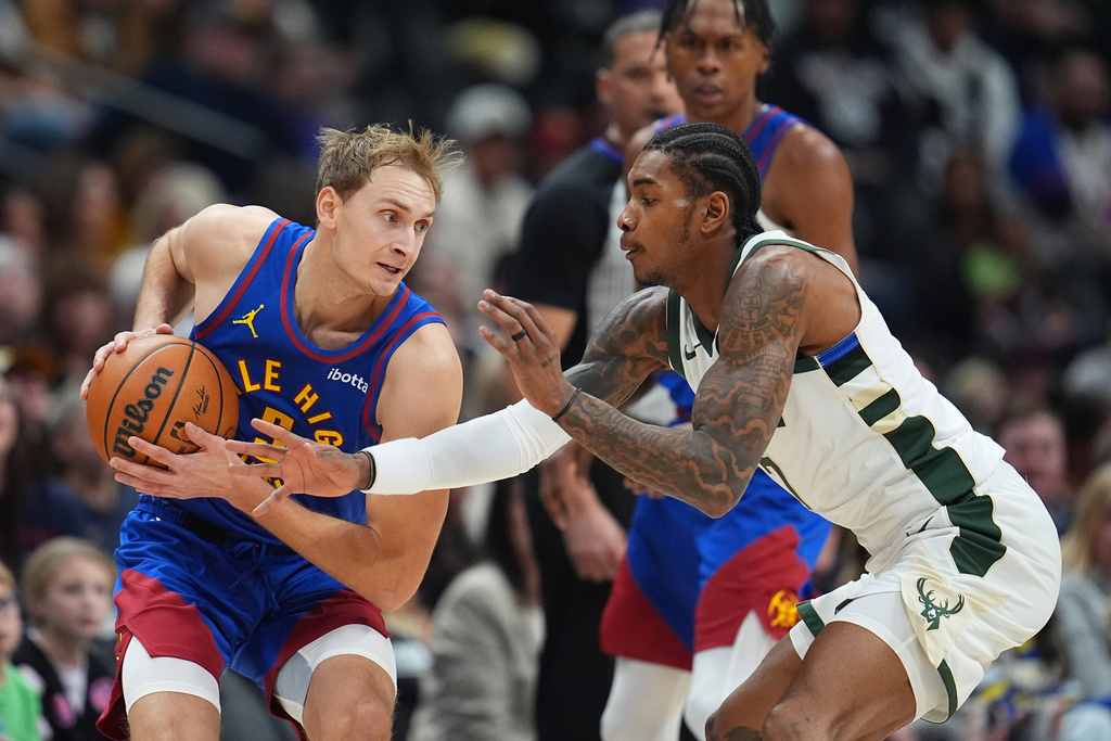Milwaukee Bucks guard Kevin Porter Jr., right, tries to steal the ball form Denver Nuggets forward Hunter Tyson in the first half of an NBA basketball game, Sunday, Jan. 11, 2026, in Denver. (AP Photo/David Zalubowski)
