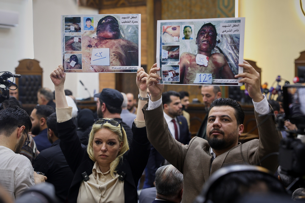 Human rights activists hold photos of children killed at the start of the Syrian uprising in Daraa during the first trial session of Atef Najib, former head of the Political Security Branch in Daraa during Bashar Assad's rule, at the Palace of Justice in Damascus, Syria, Sunday, April 26, 2026. (AP Photo/Ghaith Alsayed)