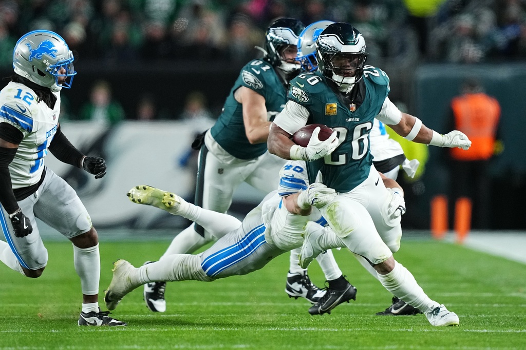 Philadelphia Eagles running back Saquon Barkley (26) is tripped up by Detroit Lions linebacker Jack Campbell (46) during the second half of an NFL football game Sunday, Nov. 16, 2025, in Philadelphia. (AP Photo/Matt Rourke)