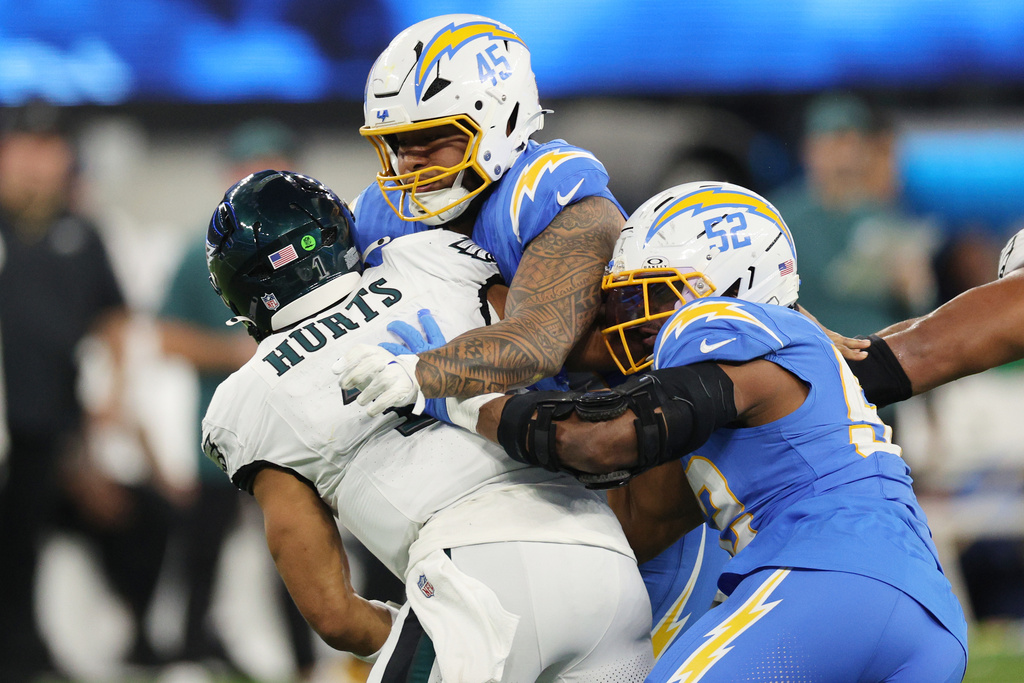 Philadelphia Eagles quarterback Jalen Hurts (1) is tackled by Los Angeles Chargers linebacker Tuli Tuipulotu (45) and outside linebacker Khalil Mack (52) during the second half of an NFL football game Monday, Dec. 8, 2025, in Inglewood, Calif. (AP Photo/Kevork Djansezian)