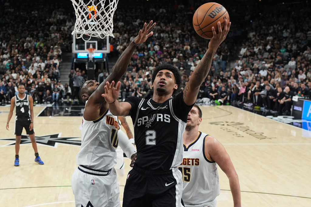 San Antonio Spurs guard Dylan Harper (2) drives to the basket against Denver Nuggets guard Tim Hardaway Jr. (10) during the first half of an NBA basketball game in San Antonio, Thursday, March 12, 2026. (AP Photo/Eric Gay)