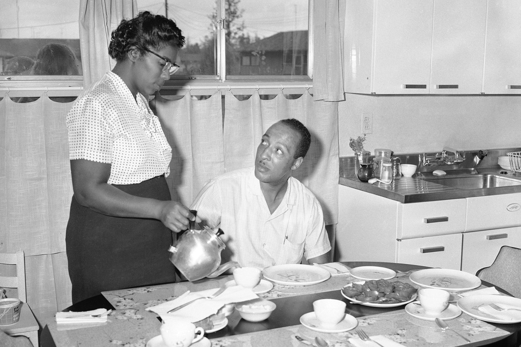 FILE - William Myers is served coffee by his wife Daisy in their new home in Levittown, Penn., Aug. 19, 1957, after they became the first black family to move into the 15,000-home all-white community. (AP Photo/Sam Myers, File)