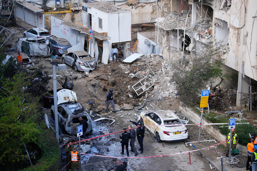 Israeli security and rescue forces respond at the site of an Iranian missile strike in Tel Aviv, Israel, Tuesday, March 24, 2026. (AP Photo/Ohad Zwigenberg)