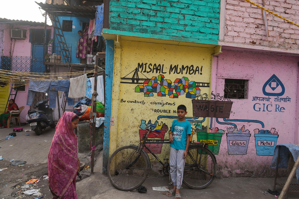 A boy stands beside a wall that shows a mural by the Rouble Nagi Art Foundation in the Dhobi Ghat area of Mumbai, India, Thursday, Feb. 5, 2026. (AP Photo/Rafiq Maqbool)