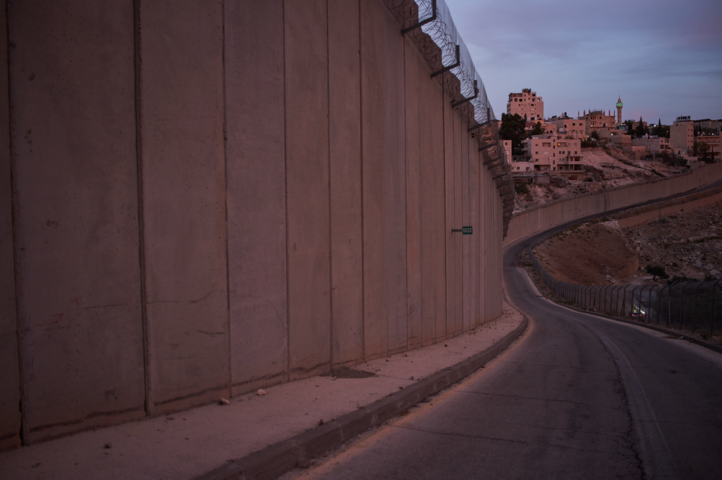 A mosque's minaret and buildings are seen in the West Bank village of Abu Dis behind the Israel's separation wall near Jerusalem, Monday, Oct. 5, 2026. (AP Photo/Leo Correa)