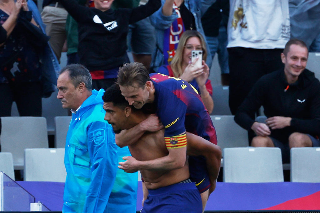 Barcelona's Frenkie de Jong hugs Ronald Araujo after a goa; during a La Liga soccer match between Barcelona and Girona in Barcelona, Spain, Saturday, Oct. 18, 2025. AP Photo/Joan Monfort)