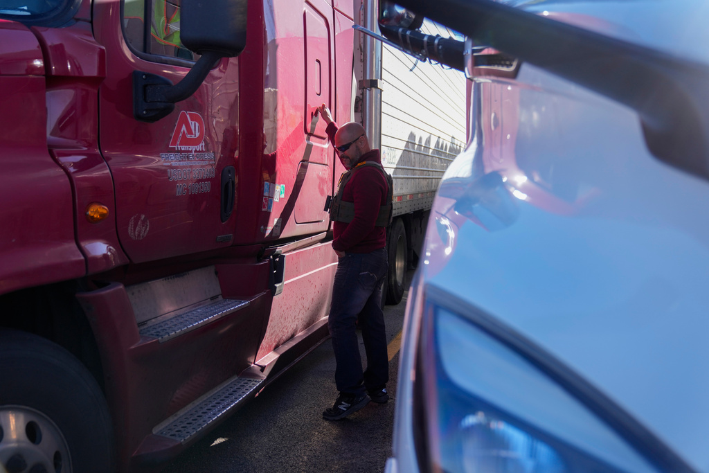 A U.S. Border Patrol agent knocks on a truck door during an immigration enforcement operation at a truck stop Monday, Nov. 3, 2025, in Hampshire, Ill. (AP Photo/Erin Hooley)