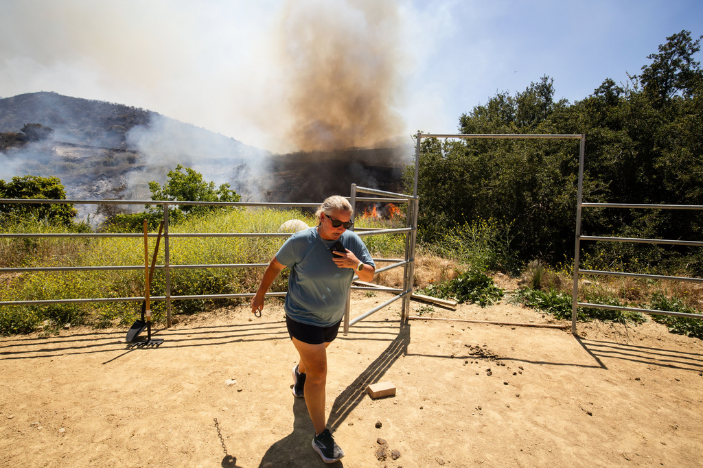 FILE - A woman steps away as the Sandy Fire approaches a neighborhood May 18, 2026, in Simi Valley, Calif. (AP Photo/Ethan Swope, File)