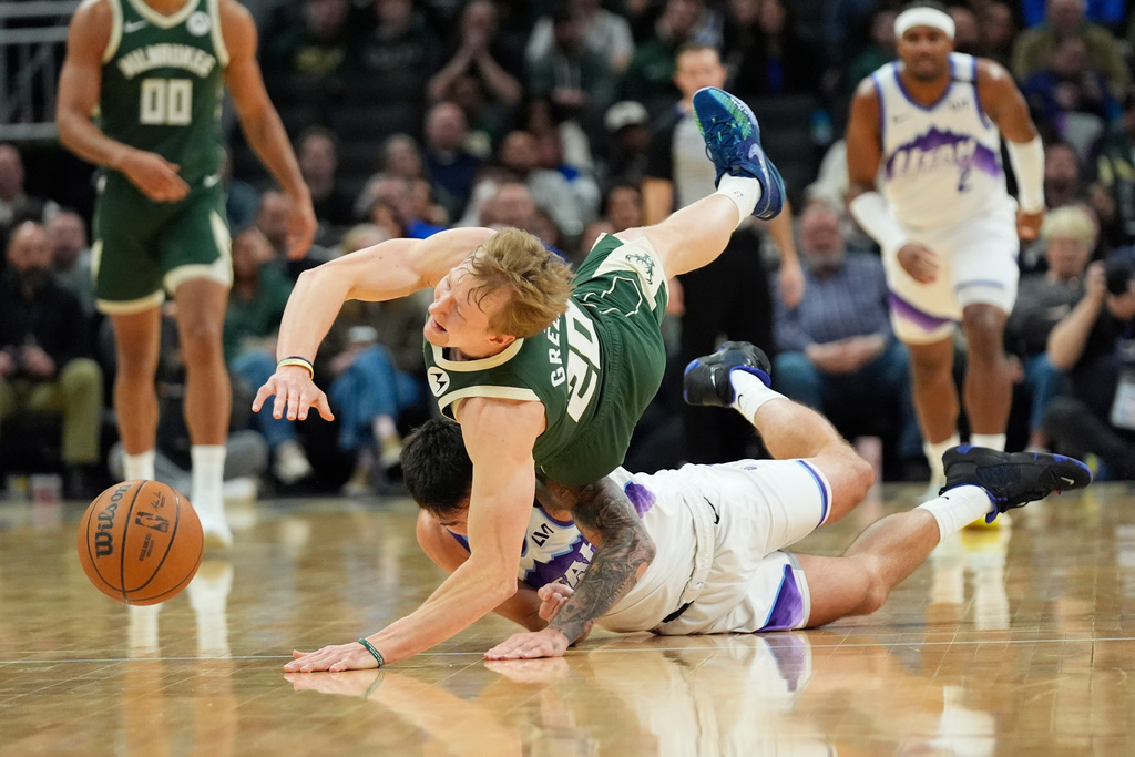 Milwaukee Bucks' AJ Green (20) and Utah Jazz's John Konchar, bottom, dive for the ball during the first half of an NBA basketball game Saturday, March 7, 2026, in Milwaukee. (AP Photo/Aaron Gash)