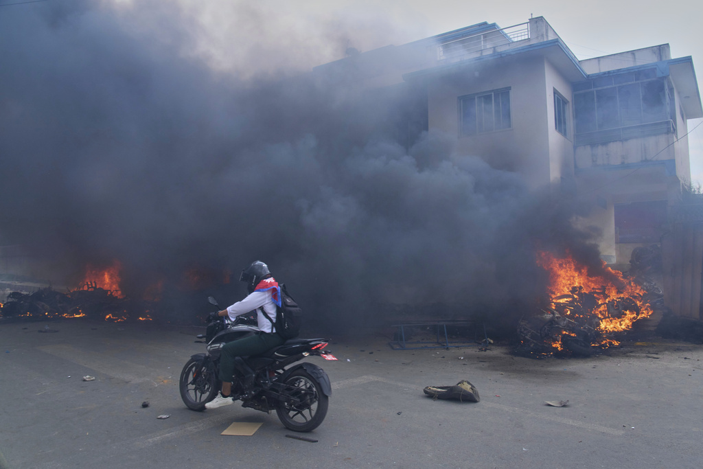 A motorcyclist drives past a burning police station during protests against social media ban and corruption in Kathmandu, Nepal, Tuesday, Sept. 9, 2025. (AP Photo/Niranjan Shrestha)