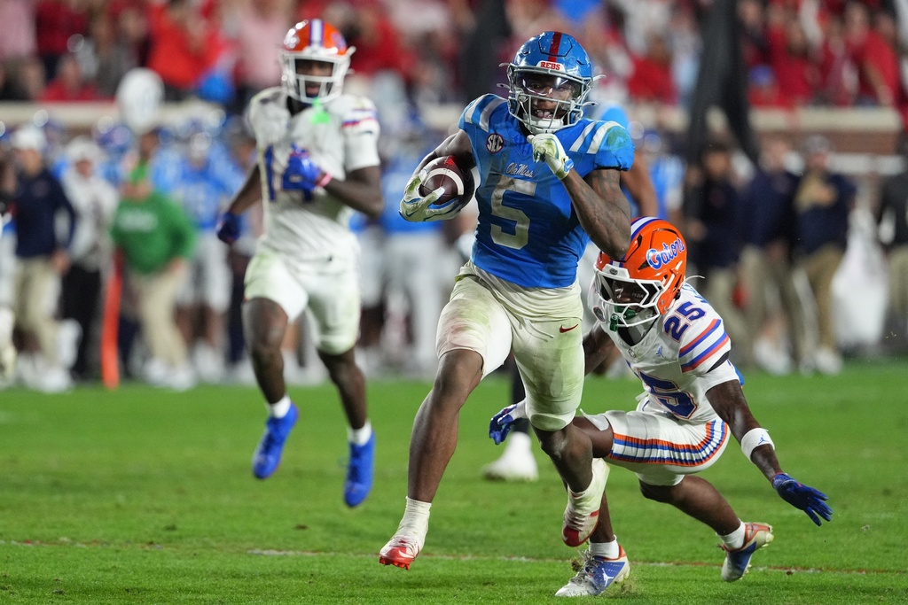 Mississippi running back Kewan Lacy (5) evades a tackle attempt by Florida cornerback Cormani McClain and safety Jordan Castell during the second half of an NCAA college football game, Saturday, Nov. 15, 2025, in Oxford, Miss. (AP Photo/Rogelio V. Solis)