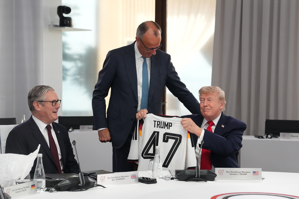 El presidente de Estados Unidos, Donald Trump, a la derecha, sostiene una camiseta con el número 47 mientras el primer ministro británico, Keir Starmer, a la izquierda, y el canciller alemán, Friedrich Merz, miran durante una sesión de trabajo en la cumbre del G7 en Evian-les-Bains, Francia, el martes 16 de junio de 2026. (AP Foto/Thibault Camus, Pool)