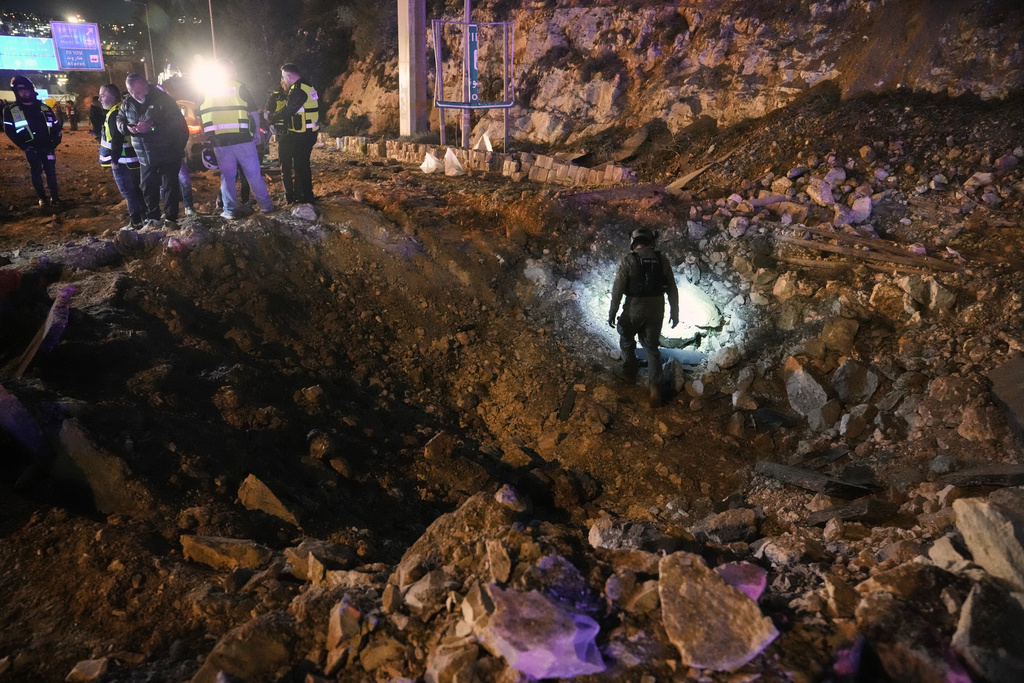 Israeli security forces inspect a damaged road after a missile launched from Iran struck Jerusalem, Sunday, March 1, 2026.(AP Photo/Mahmoud Illean)