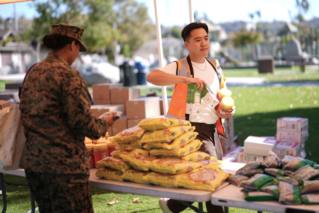 Volunteer Angus Hsigh helps a military member during a Feeding San Diego food distribution for military families affected by the federal shutdown Friday, Nov. 7, 2025, in Oceanside, Calif. (AP Photo/Gregory Bull)