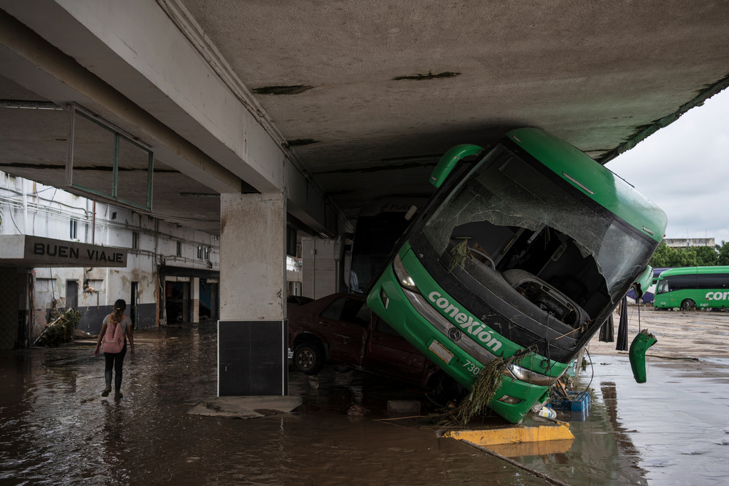 A woman walks through a damaged bus station after heavy rainfall in Poza Rica, Veracruz state, Mexico, Saturday, Oct. 11, 2025. (AP Photo/Felix Marquez)