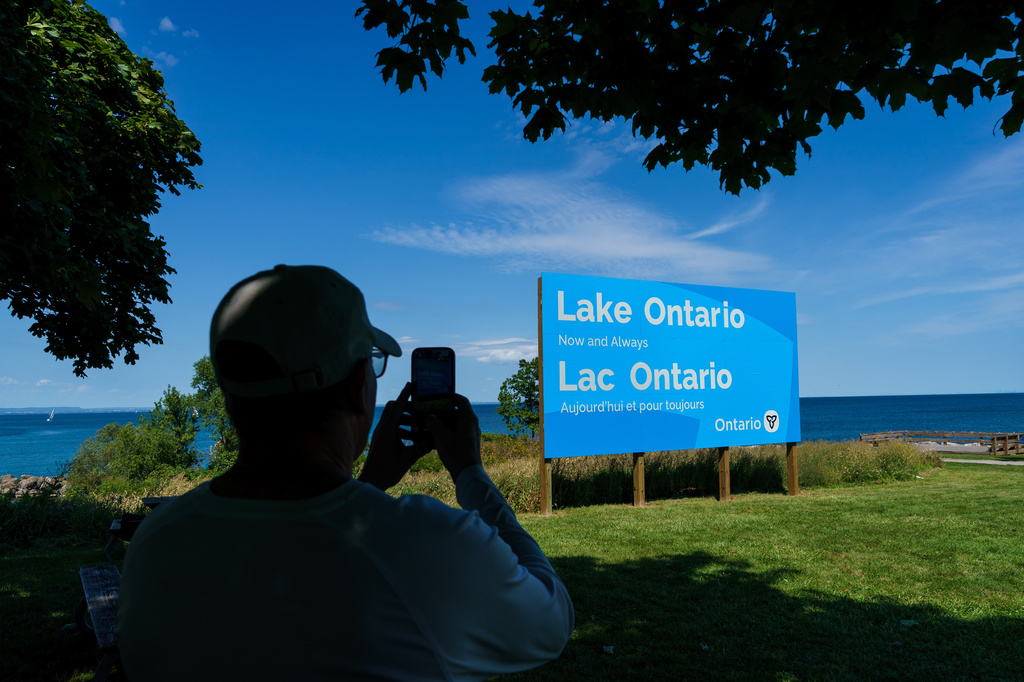 A person takes a picture of the newly unveiled sign for Lake Ontario at Fifty Point Conservation Area in Grimsby, Ontario, Canada, on Saturday, Aug. 29, 2026. (Keito Newman/The Canadian Press via AP)