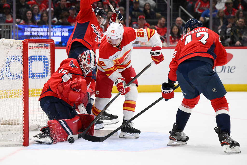 Calgary Flames center Ryan Strome (22) battles for the puck against Washington Capitals goaltender Logan Thompson (48) and defenseman Martin Fehérváry, right, during the second period of an NHL hockey game, Monday, March 9, 2026, in Washington. (AP Photo/Nick Wass)