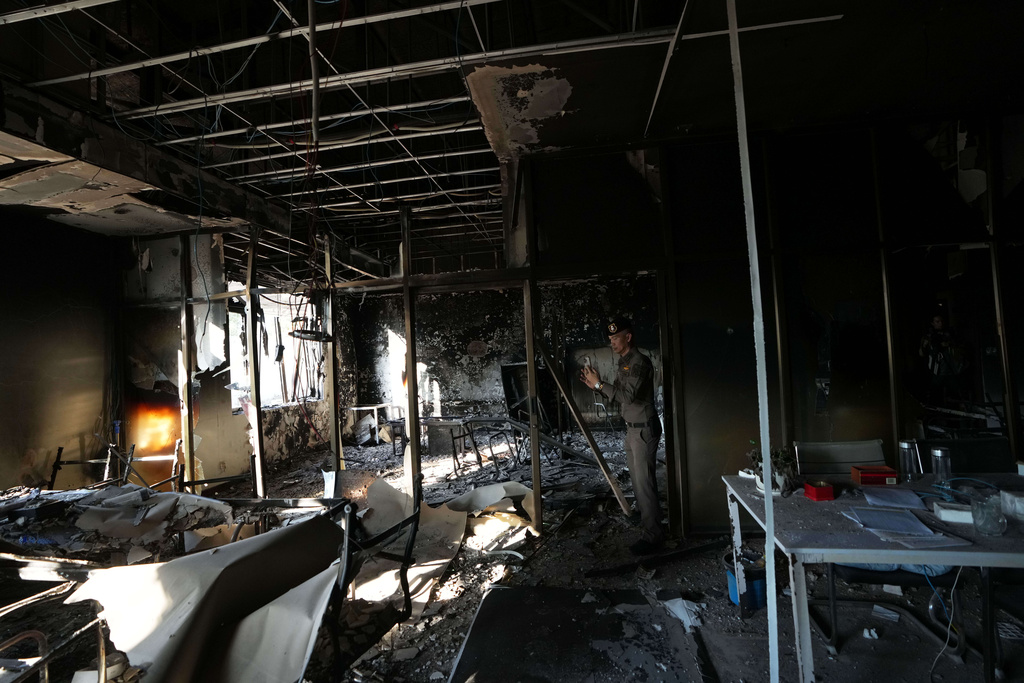 A Thai policeman inspects a damaged work station at a scam compound in O'Smach, Cambodia, Monday, Feb. 2, 2026, (AP Photo/Sakchai Lalit)