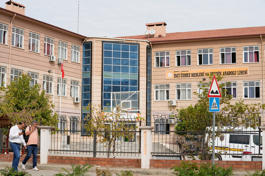 People walk past a vocational and technical high school in the Turgutlu district of Manisa province, western Turkey, Tuesday, Sept. 22, 2026, after a gunman opened fire near the school. (IHA via AP)