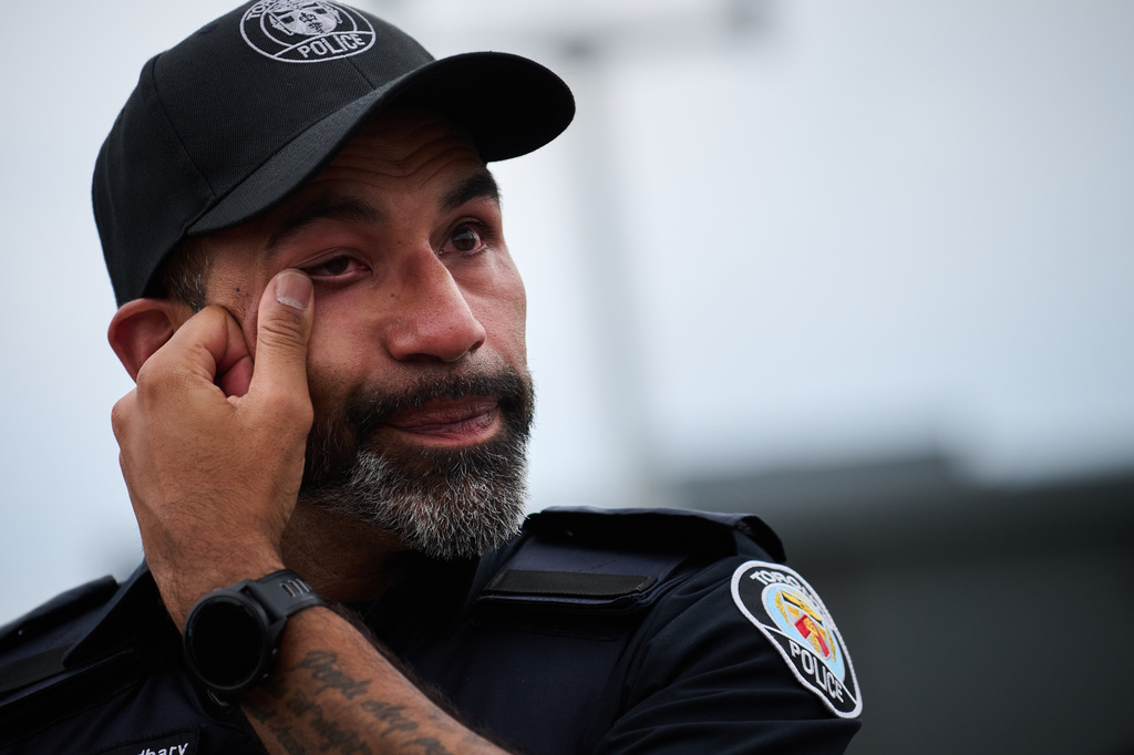 A police officer wipes away a tear after a procession with the body of Toronto Police Const. Marc Pinizzotto, who was killed in the line of duty, at the Chief Coroner's office in Toronto, Thursday, June 11, 2026. (Sammy Kogan/The Canadian Press via AP)