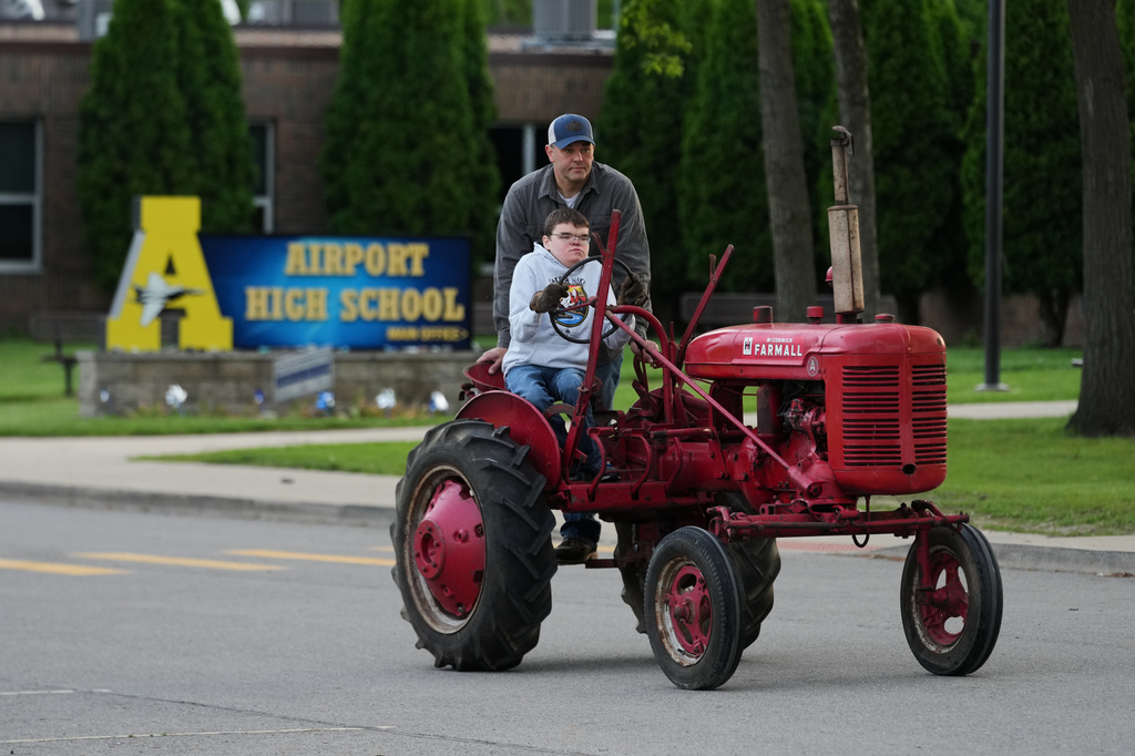 Austin Neddo drives a 1940 Farmall A tractor with his father Shay during Tractor Day for graduating seniors at Airport High School Friday, May 22, 2026, in Carleton, Mich. (AP Photo/Paul Sancya)