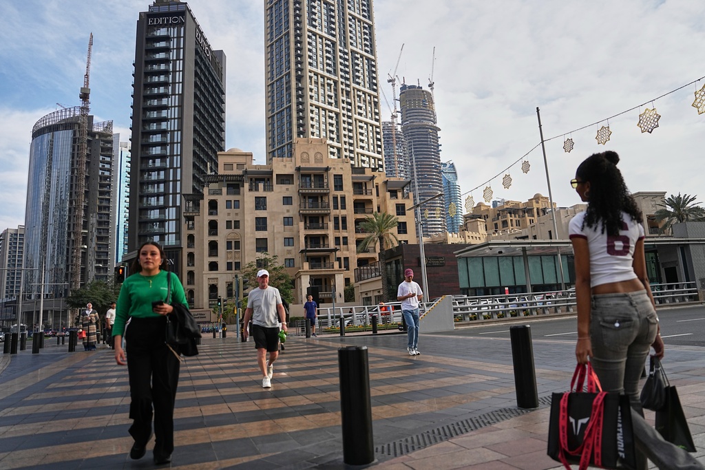 People cross a street in downtown Dubai, United Arab Emirates, Saturday, March 7, 2026. (AP Photo/ Fatima Shbair)