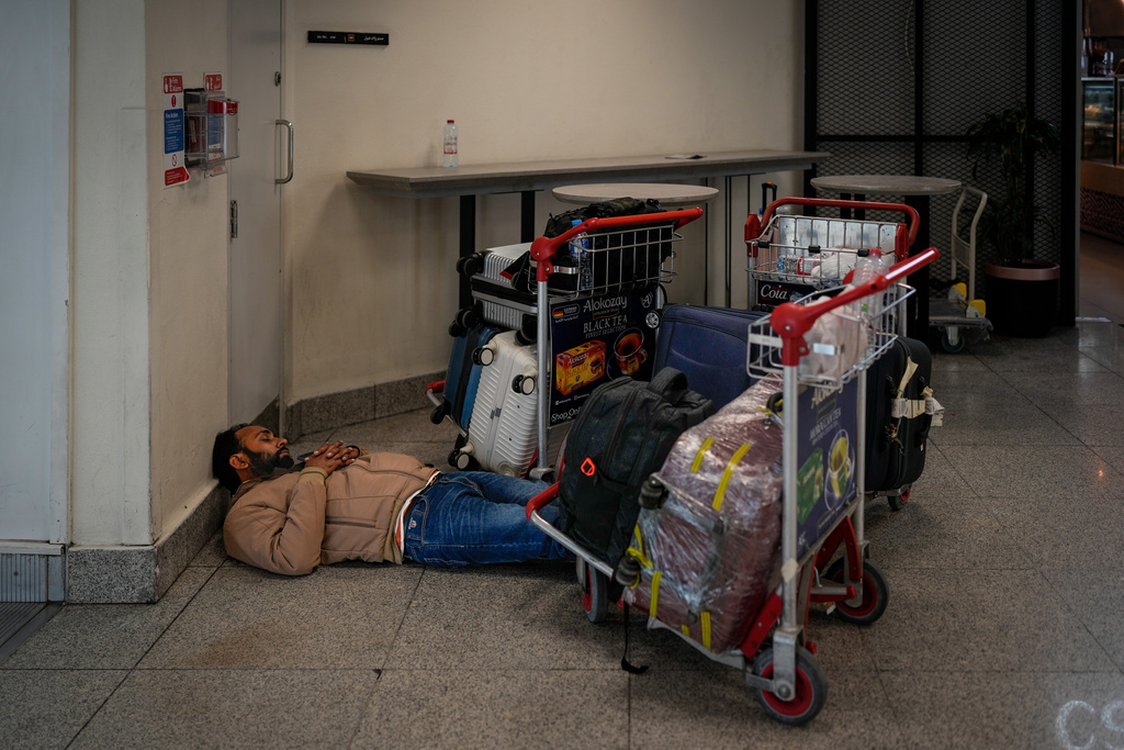 A stranded passenger sleeps on the floor outside Dubai International Airport terminal as the airport resumes limited operations in Dubai, United Arab Emirates, Thursday, March 5, 2026. (AP Photo/Altaf Qadri)