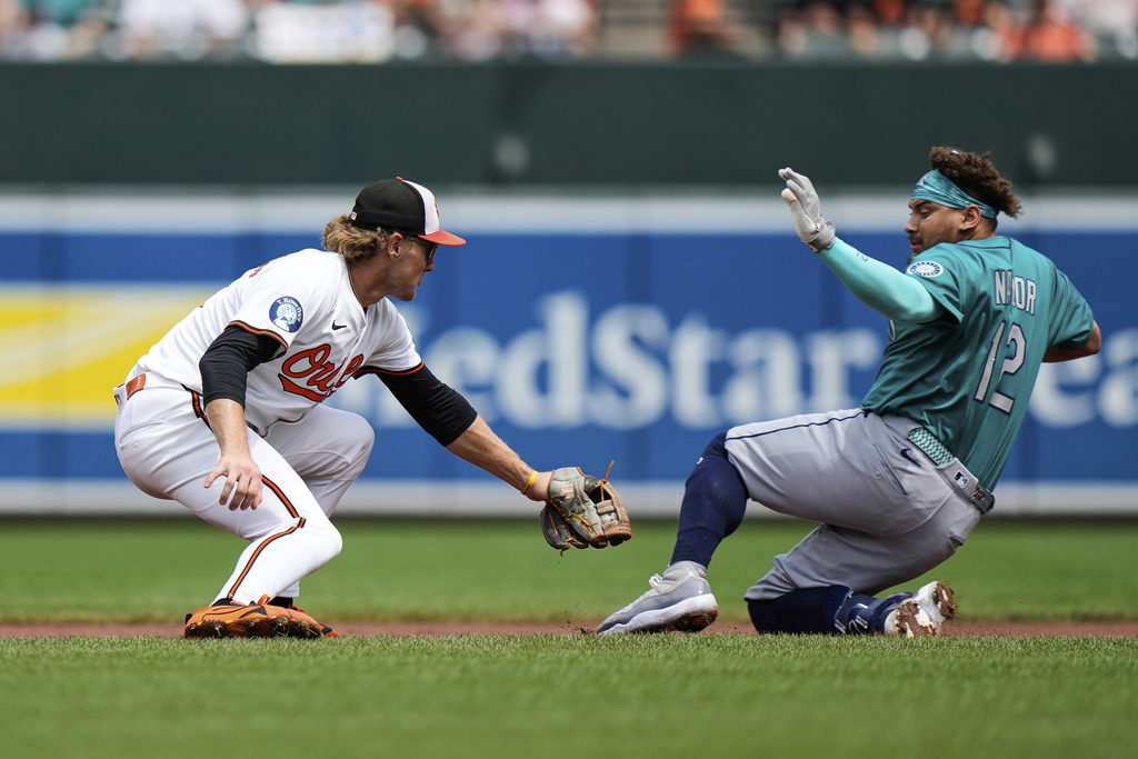Baltimore Orioles shortstop Gunnar Henderson, left, tags out Seattle Mariners' Josh Naylor (12) at second base trying to stretch a single into a double during the first inning of a baseball game, Thursday, Aug. 14, 2025, in Baltimore. (AP Photo/Stephanie Scarbrough)