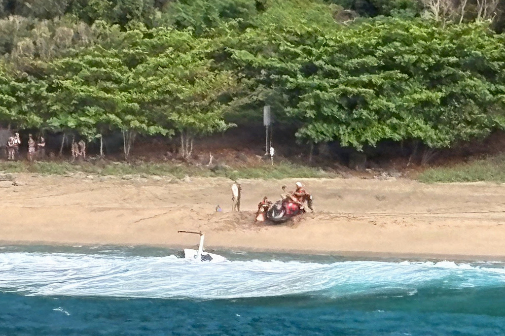 Kauai Ocean Safety members and other people assist individuals after an Airborne Aviation tourist helicopter crash on Kalalau Beach on Kauai, Hawaii, on March 26, 2026. (Petty Officer 2nd Class Tyler Robertson/Station Kauai/U.S. Coast Guard via AP)