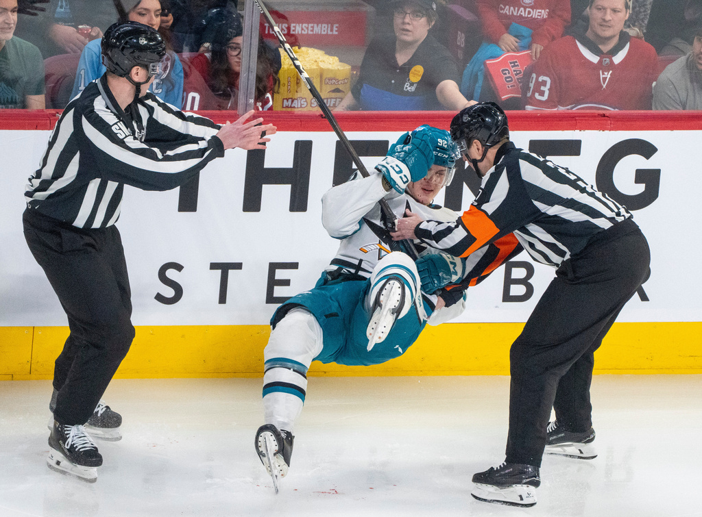 San Jose Sharks' Igor Chernyshov (92) falls to the ice as he tries to stand following a check by Montreal Canadiens' Mike Matheson (not shown) as referee Eric Furlatt (right) helps during the first period of an NHL hockey game in Montreal, Saturday, March 14, 2026. (Christinne Muschi/The Canadian Press via AP)