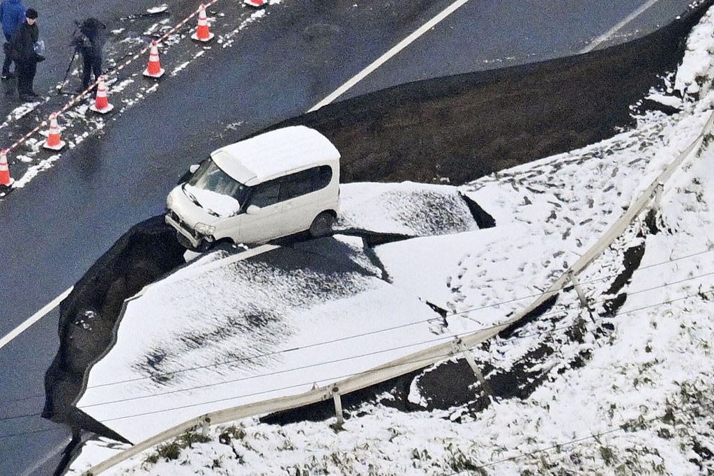 This aerial photo shows a vehicle sitting on a damaged road in Tohoku town, Aomori prefecture, northern Japan Tuesday, Dec. 9, 2025, following a powerful earthquake on late Monday. (Kyodo News via AP)