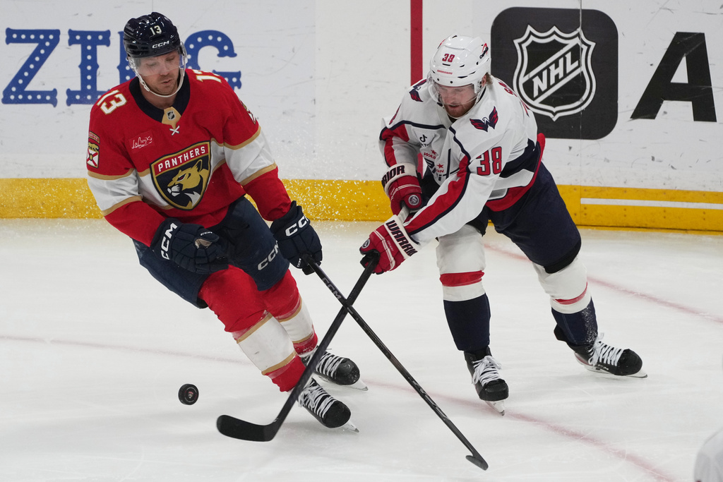 Washington Capitals defenseman Rasmus Sandin (38) passes the puck as Florida Panthers center Sam Reinhart (13) defends during the second period of an NHL hockey game, Thursday, Nov. 13, 2025, in Sunrise, Fla. (AP Photo/Marta Lavandier)