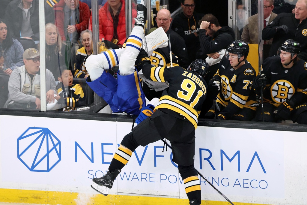 Boston Bruins' Nikita Zadorov (91) checks Buffalo Sabres' Owen Power, center left, during the first period of an NHL hockey game, Saturday, Oct. 11, 2025, in Boston. (AP Photo/Michael Dwyer)