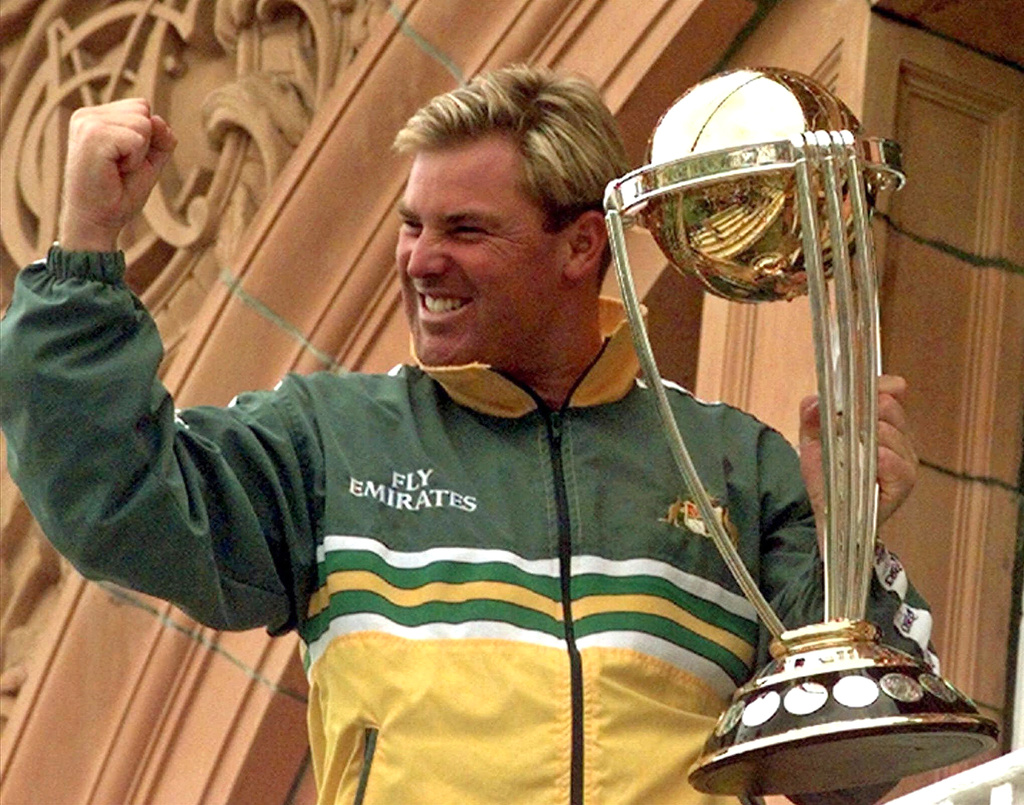 FILE - Australia's Shane Warne clenches his fist as he holds the Cricket World Cup Trophy on the team balcony at Lords after Australia defeated Pakistan by 8 wickets in the final of the Cricket World Cup, in London Sunday, June 20, 1999. (AP Photo/Rui Vieira, File)