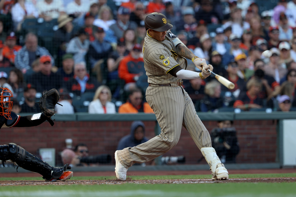 San Diego Padres' Manny Machado, right, hits a two-run home run in front of San Francisco Giants catcher Andrew Knizner, left, during the second inning of a baseball game in San Francisco, Sunday, Sept. 13, 2026. (AP Photo/Jed Jacobsohn)